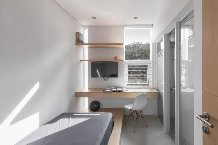 Interior kamar kost yang rapi dan minimalis, dilengkapi tempat tidur nyaman, meja belajar, dan lemari pakaian.