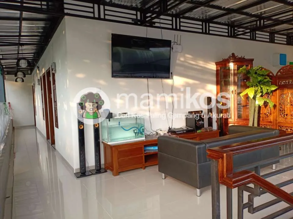 Ruang bersama di rumah kost yang nyaman dengan sofa empuk, meja kopi, dan rak buku, menciptakan suasana santai.